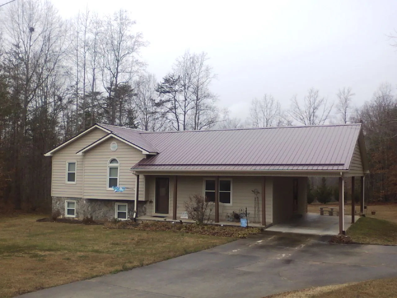 Burgundy metal roof on a tan split level home with an attached carport in Williamstown